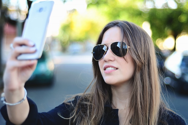 Foto mujer joven que toma selfie con su teléfono inteligente.