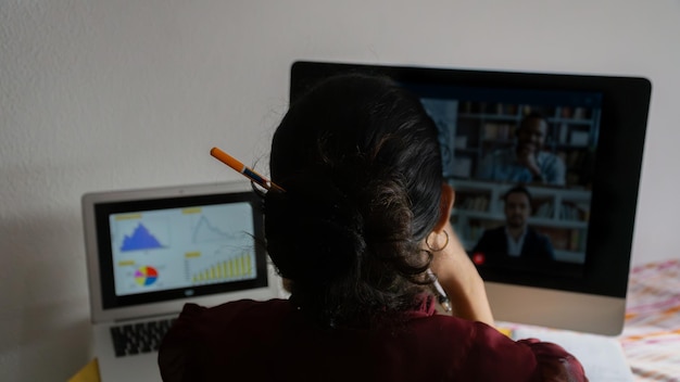 Mujer joven que trabaja desde casa sentada en una computadora en un análisis bancario con representantes