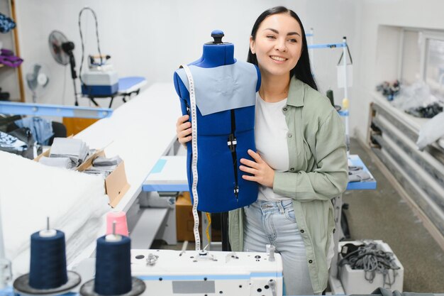 Mujer joven que trabaja como costurera en la fábrica de ropa