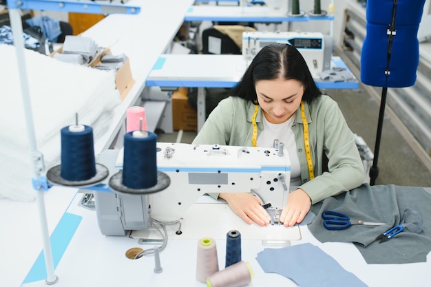 Mujer joven que trabaja como costurera en la fábrica de ropa