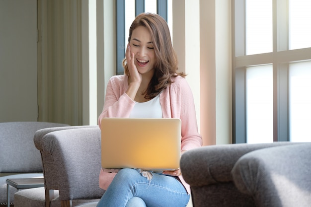 Mujer joven que trabaja de compras en línea usando computadoras portátiles y en un estado de ánimo feliz.