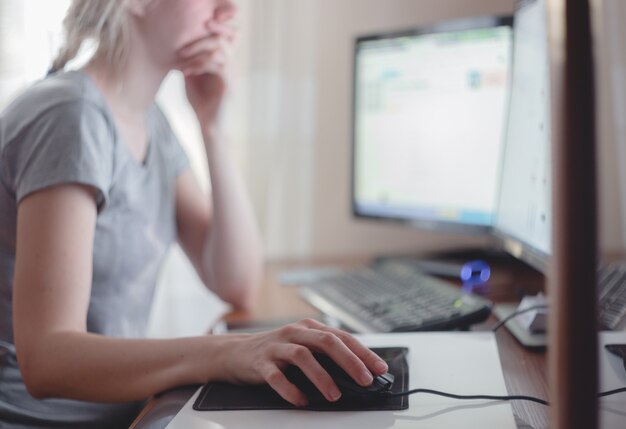 Mujer joven que trabaja con la computadora en la oficina en casa.