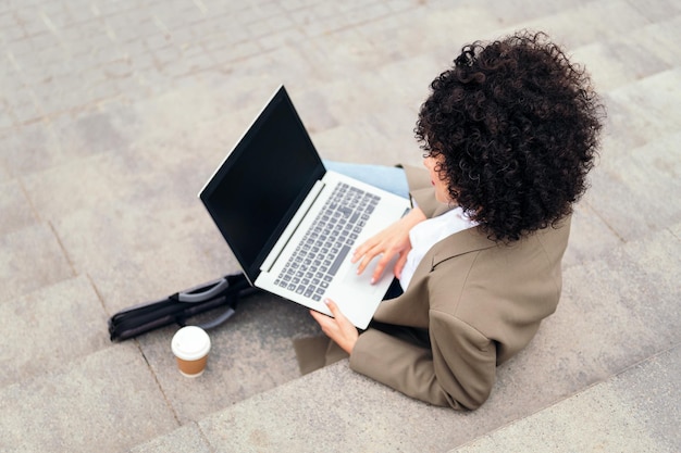 Mujer joven que trabaja con computadora portátil al aire libre