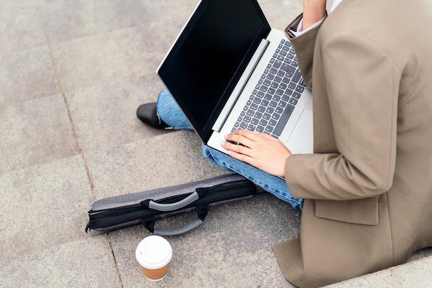 Mujer joven que trabaja con computadora portátil al aire libre