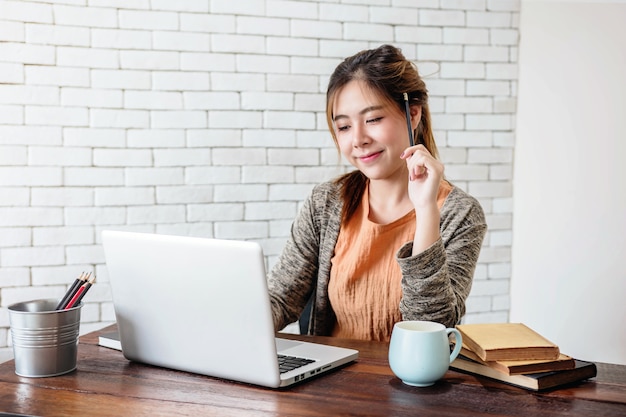 Mujer joven que trabaja en la computadora portátil en casa