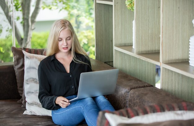 Mujer joven que trabaja en la computadora portátil mientras se queda en casa.