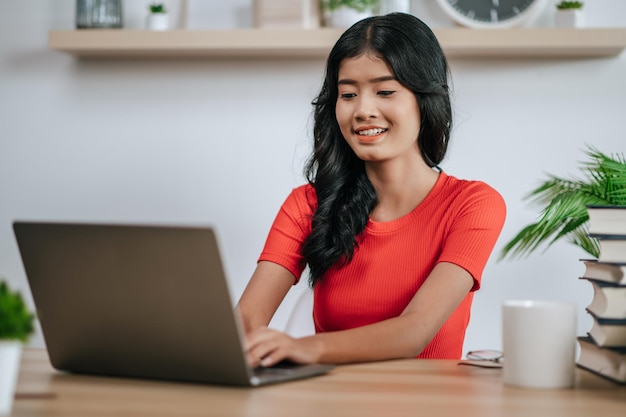 Una mujer joven que trabaja con una computadora portátil sobre la mesa.