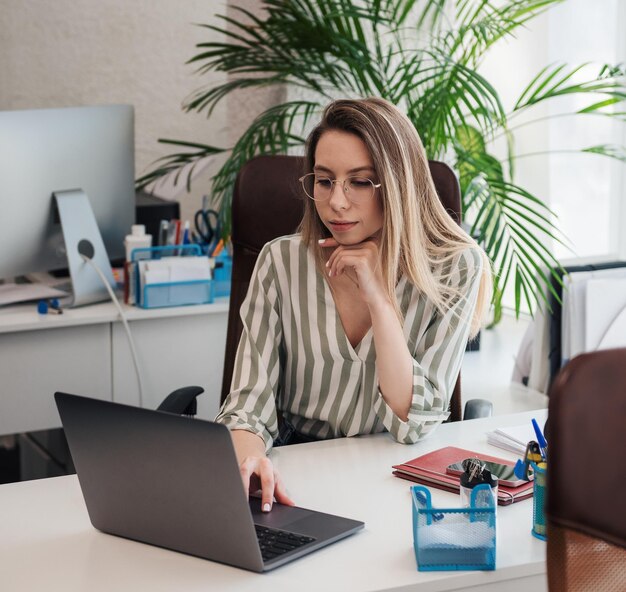 Mujer joven que trabaja en una computadora en su oficina