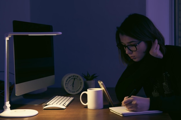 Una mujer joven que trabaja de noche en el lugar de trabajo.