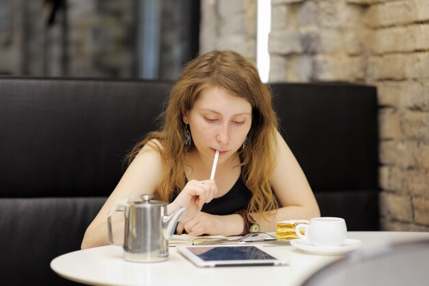 Mujer joven que trabaja o estudia en su tableta en un café