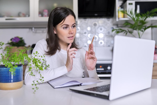 Mujer joven que trabaja en la oficina en casa usando la computadora portátil, mujer de negocios, maestra, mentora, consultora, gerente hablando, mirando la cámara web de la computadora, llamada de videoconferencia. Trabajo a distancia, estilo de vida, autónomo