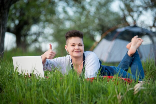 Mujer joven que usa la computadora portátil al aire libre