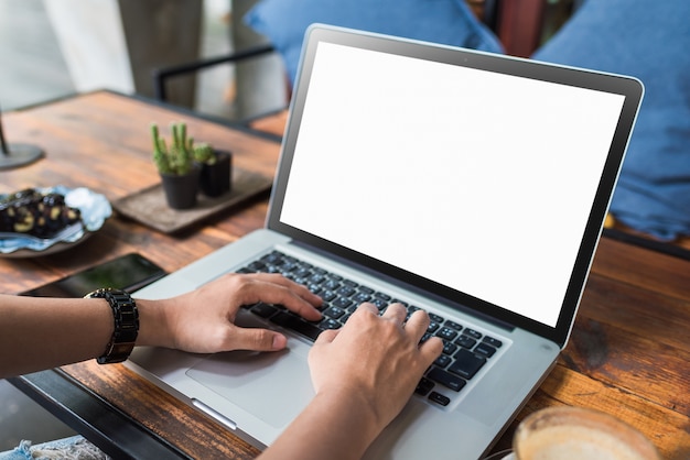 mujer joven que usa la computadora portátil en la cafetería