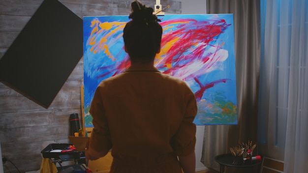 Mujer joven que usa su imaginación mientras pinta sobre lienzo.
