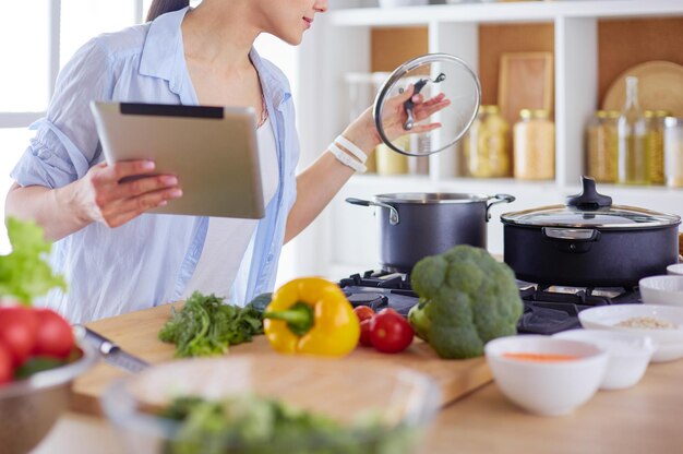 Foto mujer joven que usa una tableta para cocinar en su cocina