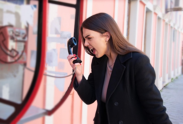 mujer joven que usa el teléfono de la calle