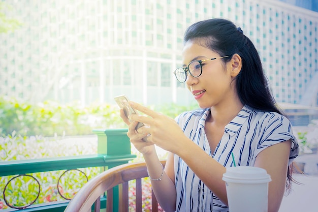 Mujer joven que usa un teléfono celular en el café