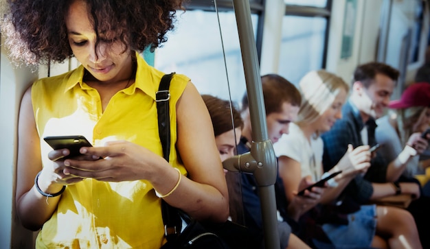 Mujer joven que usa un teléfono inteligente en un metro