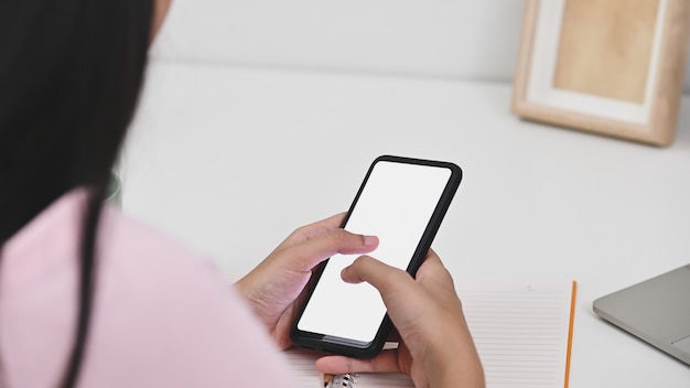 Mujer joven que usa el teléfono móvil de la pantalla aislada con el camino de recortes para el montaje.