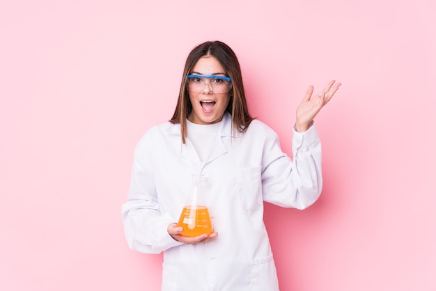 Mujer joven química aislada recibiendo una agradable sorpresa, emocionada y levantando las manos.