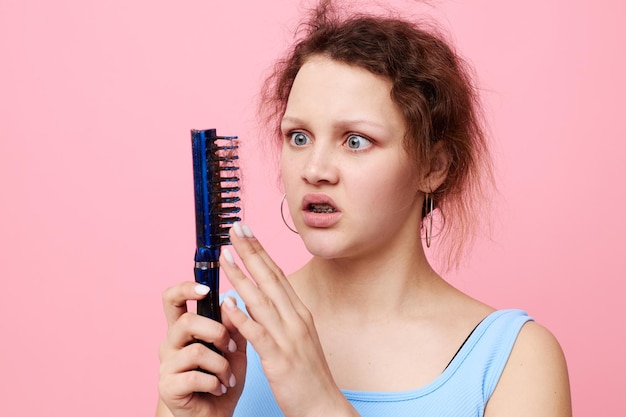 Mujer joven quita el pelo en un peine insatisfacción aislado fondo inalterado