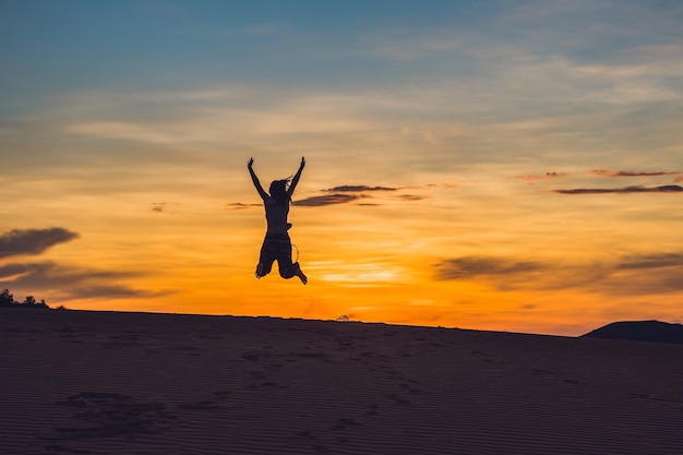 Mujer joven en rad sandy desert al atardecer o al amanecer