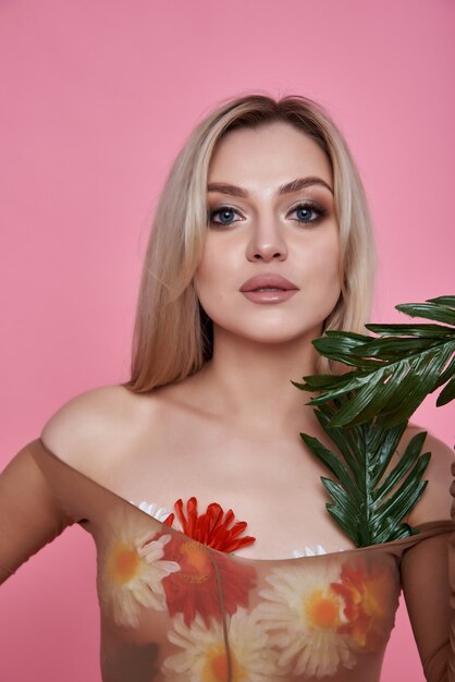 Mujer joven con un ramo de flores de primavera sobre un fondo rosa