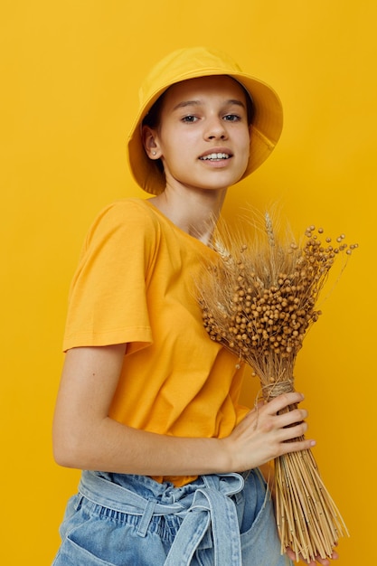 Mujer joven un ramo de flores secas en las manos Ropa casual de estilo juvenil en Hat