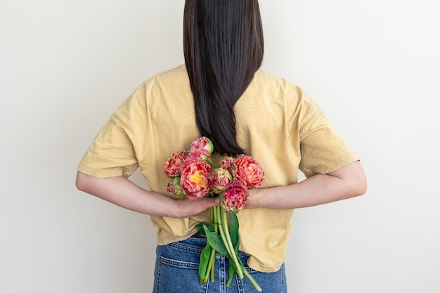 Una mujer joven con un ramo de flores sobre un fondo blanco.