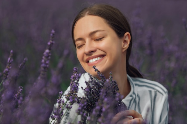 Mujer joven con ramo de lavanda sobre fondo de campo de flores violetas