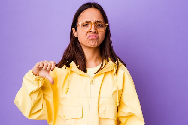 Mujer joven de raza mixta aislada mostrando el pulgar hacia abajo, concepto de decepción.