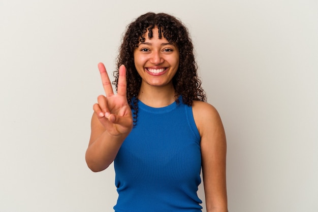 Mujer joven de raza mixta aislada en la pared blanca mostrando el signo de la victoria y sonriendo ampliamente.