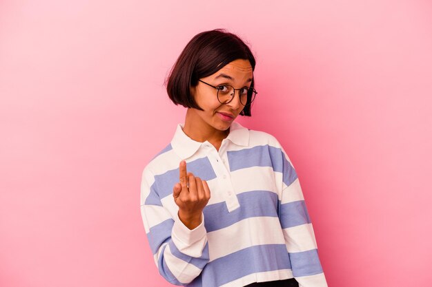 Mujer joven de raza mixta aislada en rosa apuntando con el dedo como si invitara a acercarse.