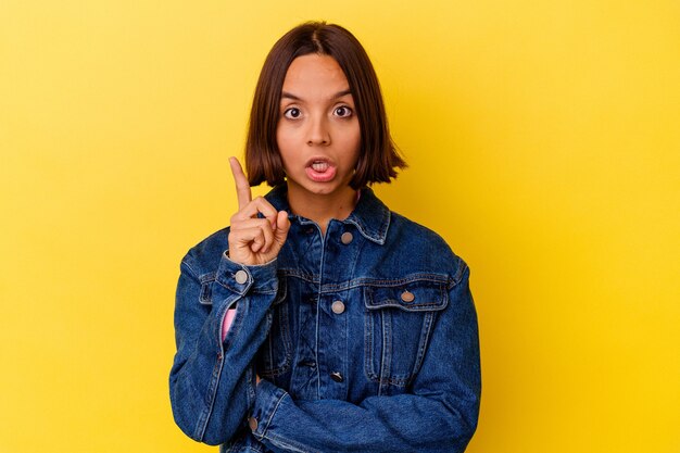 Mujer joven de raza mixta aislada sobre fondo amarillo con una idea, concepto de inspiración.