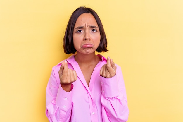 Mujer joven de raza mixta aislada sobre fondo amarillo mostrando que no tiene dinero.