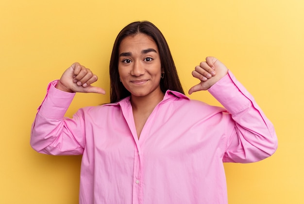 Mujer joven de raza mixta aislada sobre fondo amarillo se siente orgullosa y segura de sí misma, ejemplo a seguir.