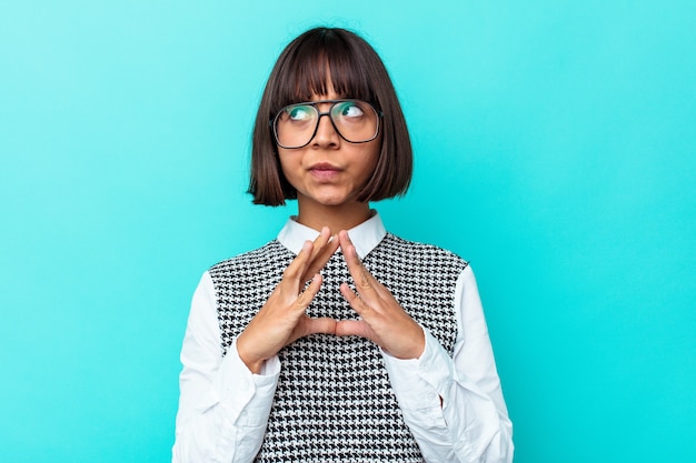 Mujer joven de raza mixta aislada sobre fondo azul haciendo un plan en mente, creando una idea.