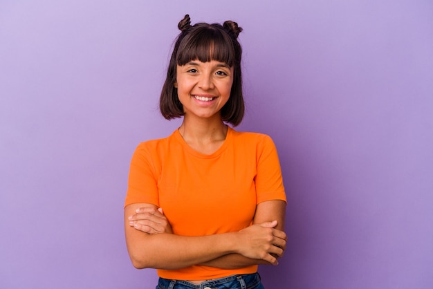 Foto mujer joven de raza mixta aislada sobre fondo púrpura que se siente segura, cruzando los brazos con determinación.