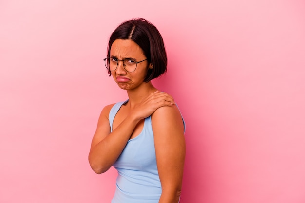 Foto mujer joven de raza mixta aislada sobre fondo rosa con dolor en el hombro.