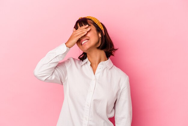 Mujer joven de raza mixta aislada sobre fondo rosa se ríe con alegría manteniendo las manos en la cabeza. Concepto de felicidad.