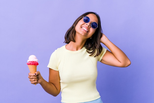 Mujer joven de raza mixta comiendo un helado estirando los brazos, posición relajada.