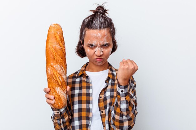 Mujer joven de raza mixta haciendo pan aislado en la pared blanca mostrando puño, expresión facial agresiva.