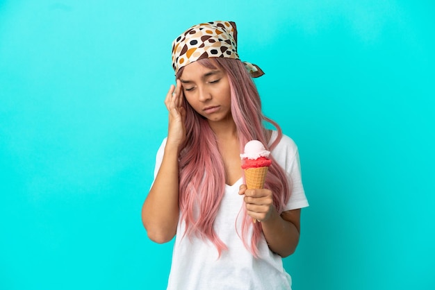 Mujer joven de raza mixta con un helado de cucurucho aislado sobre fondo azul con dolor de cabeza