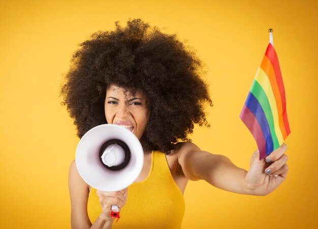 Mujer joven de raza mixta en huelga de empoderamiento de las mujeres sosteniendo la bandera del arco iris.