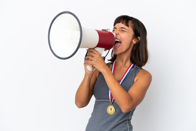 Mujer joven de raza mixta con medallas aislado sobre fondo blanco gritando a través de un megáfono