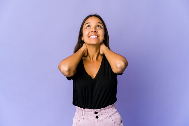 Mujer joven de raza mixta que se siente confiada, con las manos detrás de la cabeza.