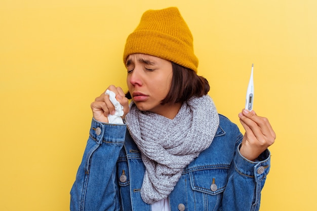 Mujer joven de raza mixta con un resfriado sobre fondo amarillo