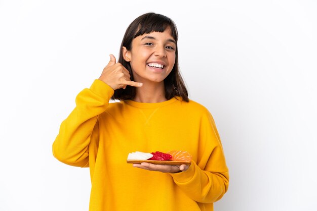 Mujer joven de raza mixta sosteniendo sashimi aislado sobre fondo blanco haciendo gesto de teléfono. Llámame señal