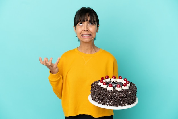 Mujer joven de raza mixta sosteniendo la torta de cumpleaños destacó abrumado