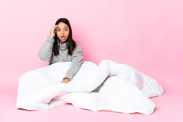 Mujer joven de raza mixta vistiendo pijama sentada en el suelo se ha dado cuenta de algo y tiene la intención de la solución